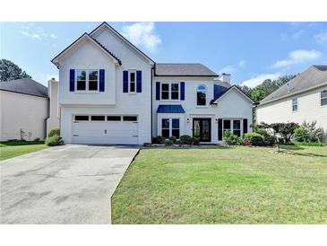 Charming two-story home featuring a well-manicured lawn, white painted brick, and a two-car garage at 9440 Knollcrest Blvd, Alpharetta, GA 30022