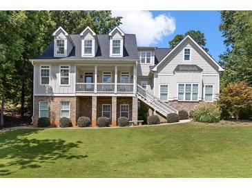 Inviting two-story home featuring a charming front porch, dormer windows, and lush landscaping at 5178 Stefan Ridge Way, Buford, GA 30519