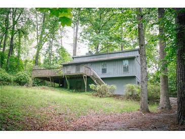Exterior view of a single Gathering home with a deck surrounded by mature trees and lush greenery at 4190 Heather Way, Cumming, GA 30041