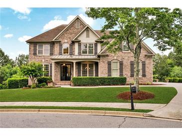Elegant brick home with lush lawn, manicured landscaping, and welcoming front porch at 1231 Ellington Ct, Cumming, GA 30041