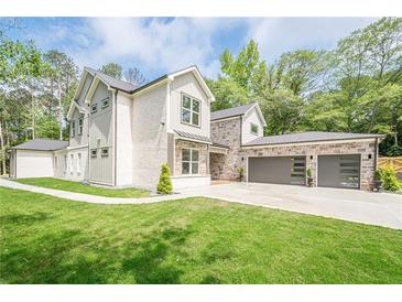 Beautiful home featuring a well-manicured lawn, a three car garage, stone accents and a grey and white color scheme at 1273 Grayson Pkwy, Grayson, GA 30017