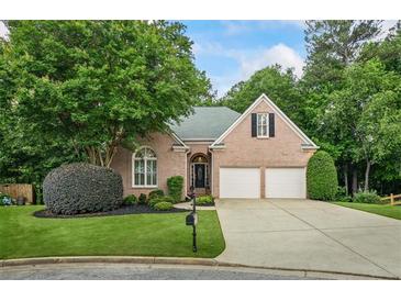 Charming brick home featuring a well-manicured lawn, two-car garage, and mature trees at 1444 Merrifield Ln, Marietta, GA 30062