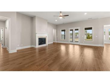Open living room featuring hardwood floors, fireplace, ceiling fan and backyard access at 1609 Tielman Way, Snellville, GA 30078