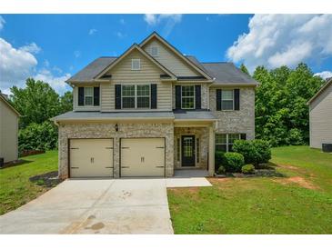 Charming two-story home features a brick facade, two-car garage and lush green lawn at 917 Revere Way, Hampton, GA 30228