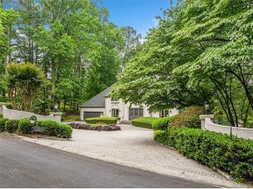 Stunning exterior view of a luxurious home with a circular driveway and lush landscaping at 550 Atlanta Country Club Se Dr, Marietta, GA 30067