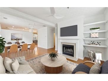 Bright open-concept living room with fireplace, built-in shelving, and an adjacent dining area at 106 Weatherstone Square Drive, Woodstock, GA 30188