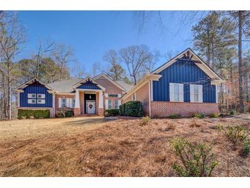 Inviting exterior of a brick and blue home with dormers, front yard, and mature trees under a sunny blue sky at 410 Fitzgerald Ln, Fayetteville, GA 30215