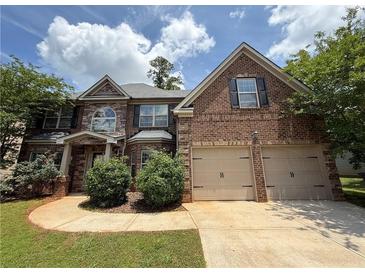 Charming brick home with a two-car garage, manicured lawn, and beautiful landscaping at 381 Plymstock Dr, Mcdonough, GA 30253