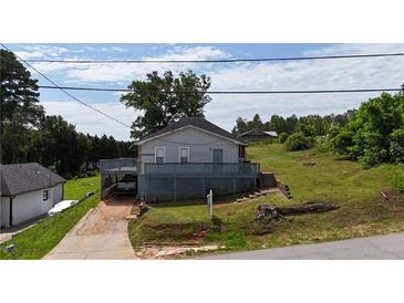 Cozy home featuring a deck, mature trees, and a unique carport underneath the rear of the house at 380 South St, Buford, GA 30518