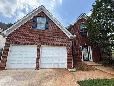 Charming red brick two-story home featuring a two-car garage, black shutters, and manicured lawn at 330 Kentwood Springs Dr, Hampton, GA 30228