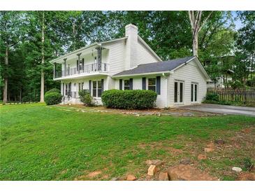 Charming white home featuring a double-decker balcony, lush lawn, and mature trees at 5290 River Mill Cir, Marietta, GA 30068