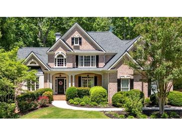 Beautiful two-story brick home featuring a landscaped front yard with lush green trees at 1311 Cobblemill Nw Way, Kennesaw, GA 30152