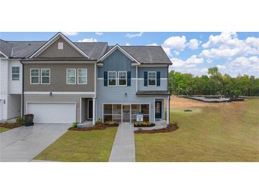 Charming two-story townhome featuring a manicured lawn, attached garage, and craftsman-style details at 1019 Merritt Dr # 102, Villa Rica, GA 30180