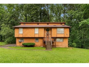 Two-story home with wood siding, lawn, and mature trees at 1822 Oriole Trl, Lithia Springs, GA 30122