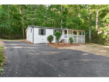 Charming home with a covered front porch, dark shutters, and an asphalt driveway surrounded by lush trees at 4212 Bryan Se Dr, Acworth, GA 30102