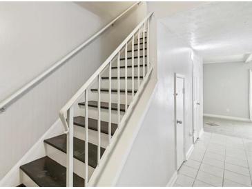 Bright staircase features painted white walls, white banister, and contrasting dark stained stairs at 6429 Woodstone Way, Morrow, GA 30260