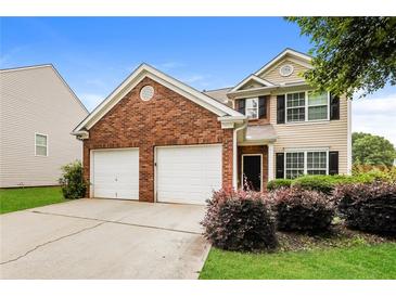 Two-story home with brick and siding, a two-car garage, and manicured landscaping at 11576 Kades Trl, Hampton, GA 30228