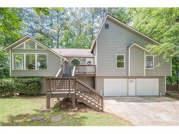 Two-story home featuring wood and siding exterior, multi-car garage, and an elevated wooden front porch and entry at 2071 Arrowhead Trl, Marietta, GA 30062