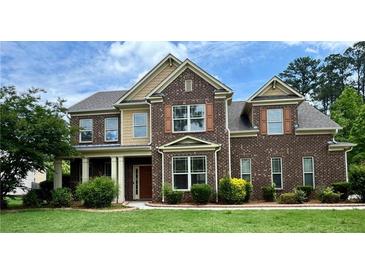 Beautiful two-story brick home with a manicured lawn and mature landscaping at 321 Champions Dr, Fairburn, GA 30213