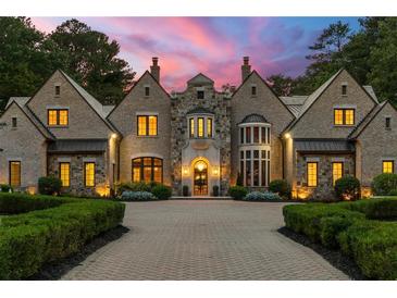 Stunning stone and brick home featuring a circular driveway, manicured landscaping, and elegant architectural details at 4560 Harris Trl, Atlanta, GA 30327