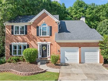 Charming two-story brick home with a well-manicured front yard and two-car garage, surrounded by mature trees at 2346 Unicoi Ct, Duluth, GA 30097
