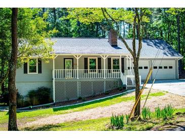 Charming home featuring a welcoming front porch, a two-car garage, and mature trees at 6026 Belle Meade Ct, Villa Rica, GA 30180