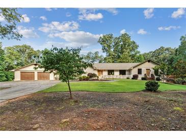 Charming ranch-style home featuring lush green lawn, mature trees, and a detached two-car garage at 980 Casteel Rd, Powder Springs, GA 30127