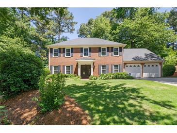 Charming two-story brick home features a well-manicured lawn, mature trees, and a three-car garage at 1850 Linnet Ne Ct, Roswell, GA 30075