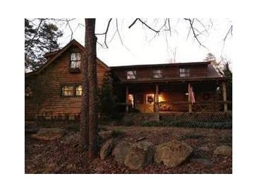 Inviting rustic log home featuring a cozy front porch and a beautifully wooded setting at 6965 Flowery Branch Rd, Cumming, GA 30041