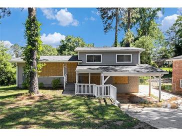 Charming two-story house with a covered car port and damaged windows at 2641 Clifton Springs Rd, Decatur, GA 30034