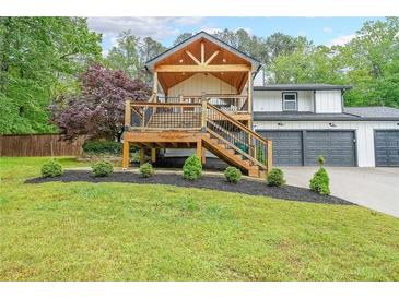 Charming home exterior featuring a wood deck, landscaped yard, and attached two-car garage at 110 W Putnam Ferry Rd, Woodstock, GA 30189