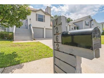 Charming two-story home features a well-manicured lawn, gray stairs and a two-car garage at 7262 Sandpiper Way, Riverdale, GA 30274