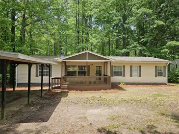 Inviting single-story home with a cozy front porch, carport, and neutral siding surrounded by lush trees at 85 Holly Dr, Carrollton, GA 30116