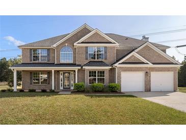 Charming two-story brick home featuring a well-manicured lawn, two-car garage and beautiful landscaping at 191 Kyndal Dr, Hampton, GA 30228