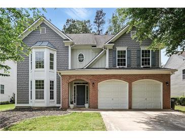 Charming two-story home featuring a brick facade, gray siding, and a two-car garage at 4975 Skyland Pkwy, Cumming, GA 30028