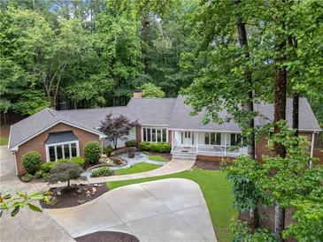 Charming brick home with lush landscaping, a circular driveway and a covered front porch at 630 Buttercup Trce, Johns Creek, GA 30022