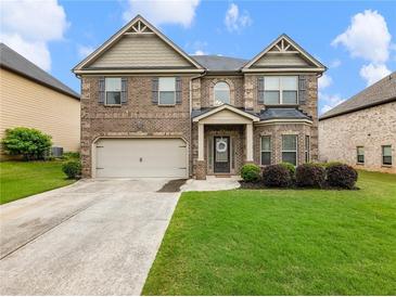 Charming two-story brick home with a well-manicured lawn and inviting curb appeal and an attached two car garage at 2490 Tack Hill Ct, Dacula, GA 30019