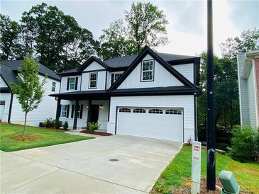 Charming two-story home boasts a two-car garage, black trim, and lush landscaping at 1540 Ox Bridge Ct, Lawrenceville, GA 30043