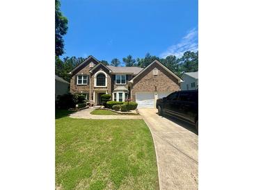 Charming brick two-story home with manicured landscaping, driveway, and a two-car garage at 7625 Cedar Grove Ct, Fairburn, GA 30213