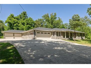 Ranch home with a three-car garage, lush landscaping and a long driveway with ample parking space at 762 Rockbridge Nw Rd, Lilburn, GA 30047