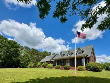 Charming brick home featuring a large lawn, mature trees and inviting covered front porch at 238 Marks Rd, Mansfield, GA 30055