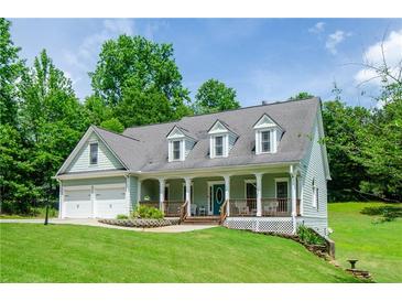 Charming two-story home features a welcoming front porch, well-manicured lawn, and an attached two-car garage at 410 Hendon Rd, Woodstock, GA 30188