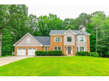 Charming two-story brick home featuring a three-car garage and a well-manicured lawn with mature trees at 3394 Floral Ct, Suwanee, GA 30024