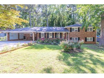 Charming brick home with a well-manicured lawn and colorful flowerbeds in a peaceful, wooded setting at 2648 Oswood Dr, Tucker, GA 30084