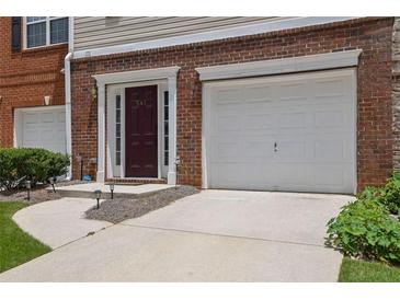 Exterior of townhome with brick facade, driveway, front door, and attached one car garage at 541 Lantern Wood Dr, Scottdale, GA 30079
