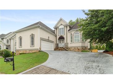 Stately home featuring manicured lawn, stone accents, and a three-car garage at 4770 Powers Park Ne Ct, Marietta, GA 30067