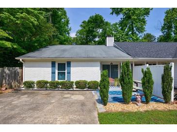 Charming single-story home with white brick, blue shutters and a welcoming, landscaped front yard at 1915 Cooper Landing Se Dr, Smyrna, GA 30080