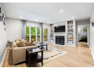 Bright living room features a fireplace, built-in shelves, and access to a balcony with wooded views at 472 Sherman Way, Decatur, GA 30033