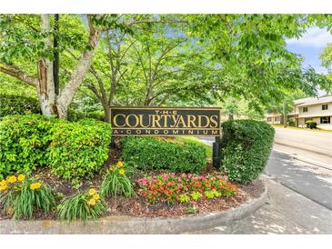 Entrance sign for The Courtyards A Condominium, surrounded by colorful landscaping at 472 Sherman Way, Decatur, GA 30033