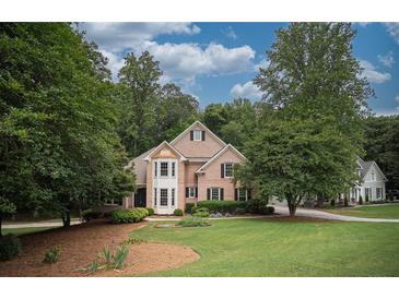 Charming two-story brick home with a well-manicured lawn and mature trees offering great curb appeal at 1325 Starboard Way, Cumming, GA 30041